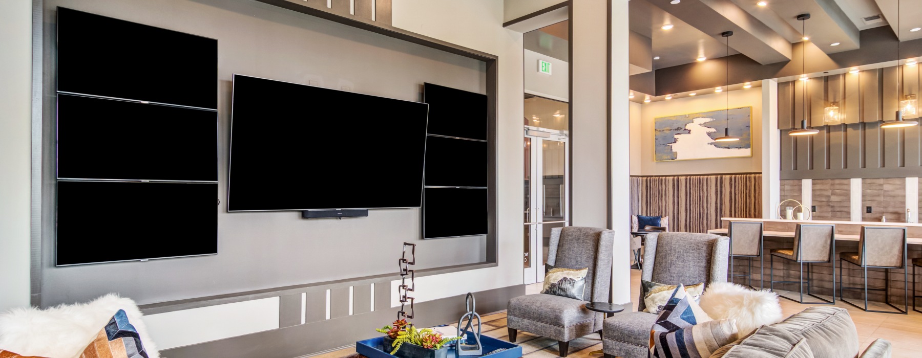 clubroom with many TVs, lounge seating, and a high top bar with additional seating.